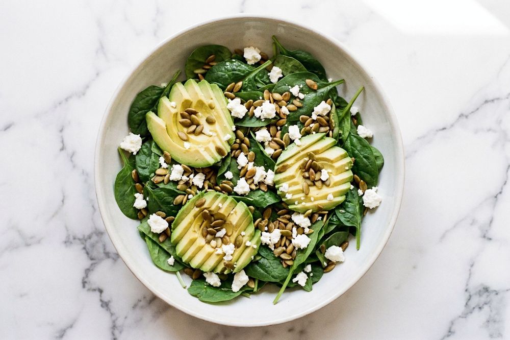 Spinach salad with sliced avocado, pumpkin seeds and lemon dressing
