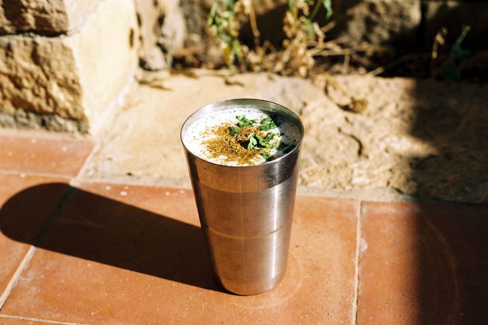 Tall glass of spiced buttermilk with cumin and fresh coriander