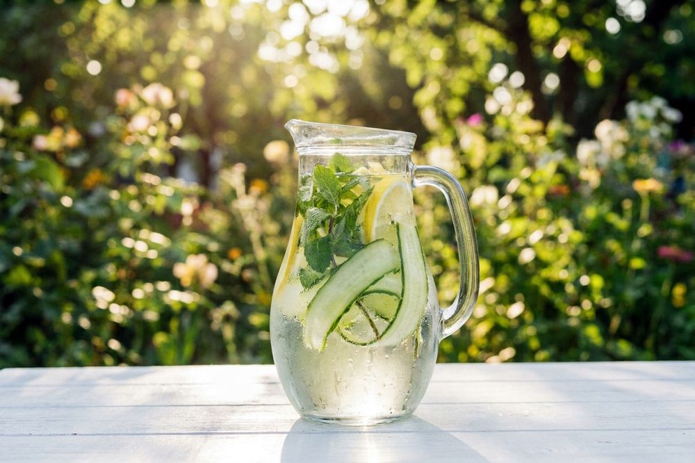 Glass pitcher of water infused with cucumber ribbons, mint and lemon