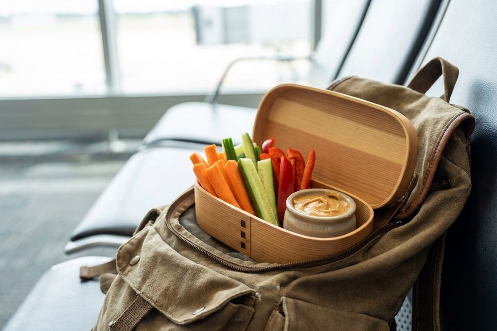 Bento box of carrot, cucumber and pepper sticks with a small pot of peanut dip
